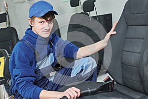 automobile detailing. Portrait of worker during car seat cleaning with vacuum cleaner