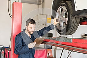 Automobile Engineer Examining Car Tire While Going Through Check