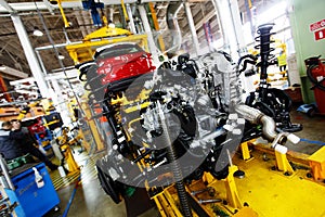 An automobile internal combustion engine stands on the conveyor line of the production hall of an automobile plant.