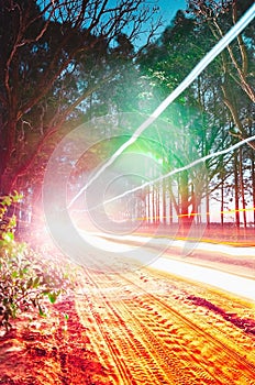 Automobile light traces passing through at a unpaved farm road s