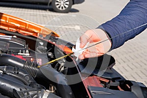 Automobile maintenance concept. Driver checking oil level in car engine dipstick. Close up