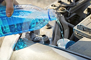 Automobile maintenance. Filling the windshield washer fluid on a car. Pouring antifreeze liquid for washing car screen