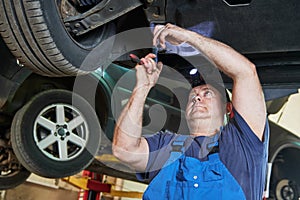 Automobile mechanic checks car suspension in service station