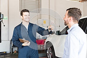 Automobile Mechanic Giving Car Key To Customer In Workshop