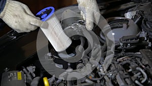 An automobile mechanic installs a new fuel filter in a car. Fuel filter replacement and fuel system maintenance, close