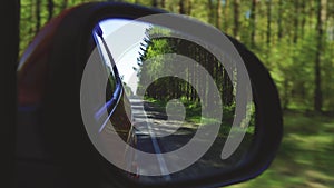 Automobile in motion. View in the rear view side mirror of a auto, driving a red car along the track