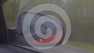 Automobile in motion. View in the rear view side mirror of a auto, driving a red car along the track