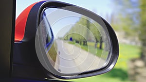 Automobile in motion. View in the rear view side mirror of a auto, driving a red car along the track