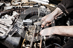 Automobile service worker or garage mechanic repairing auto car engine