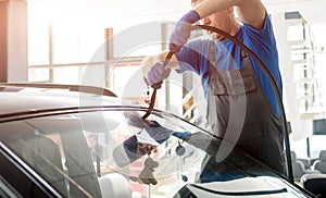 Automobile special workers remove old windscreen of a car in auto service