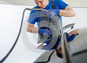 Automobile special workers remove old windscreen of a car in auto service