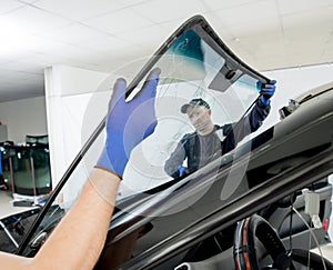 Automobile special workers remove old windscreen of a car in auto service