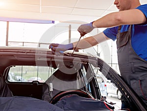 Automobile special workers remove old windscreen of a car in auto service