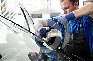 Automobile special workers remove old windscreen of a car in auto service