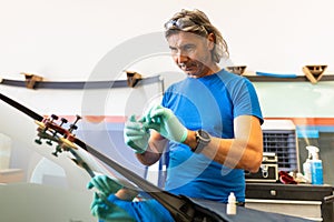 Automobile special workers remove old windscreen or windshield of a car in auto service station garage. Background