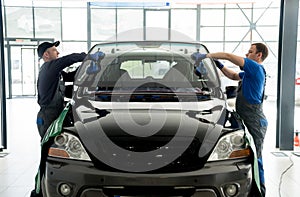 Automobile special workers replacing windscreen of a car in auto service