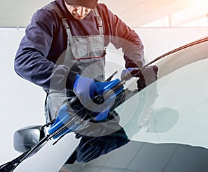 Automobile special workers replacing windscreen of a car in auto service