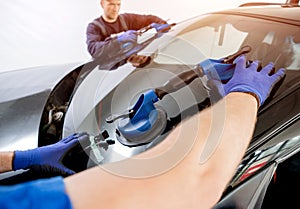 Automobile special workers replacing windscreen of a car in auto service