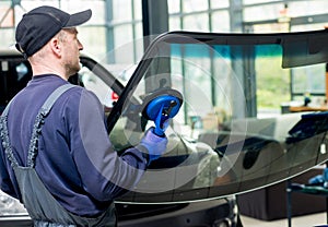 Automobile special workers replacing windscreen of a car in auto service