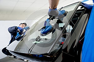 Automobile special workers replacing windscreen of a car in auto service