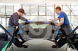 Automobile special workers replacing windscreen of a car in auto service