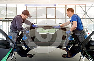 Automobile special workers replacing windscreen of a car in auto service photo