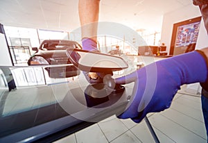 Automobile special workers replacing windscreen of a car in auto service station