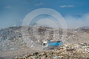 Automobile wagon at the huge garbage dump full of smoke, litter, plastic bottles,rubbish and trash at tropical island