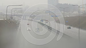 Automobiles cars drive on foggy city road. Dangerous driving conditions in winter season.