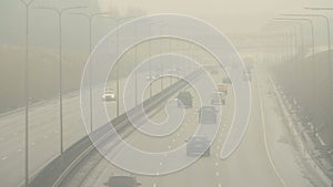 Automobiles cars drive on foggy city road. Dangerous driving conditions in winter season.