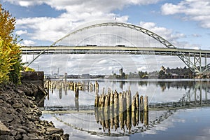 Automotive double-story arched Fremont Bridge over the Willamette River in Portland with water reflection and remnants of the