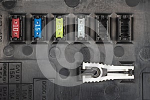 Automotive fuses on a black panel with holders and multi-colored markings - a protective device that opens the electrical circuit