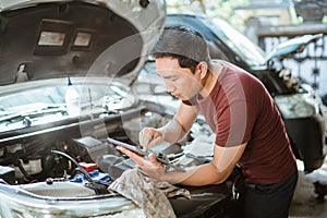 Automotive mechanic repairmen use tablets and check the system working engine