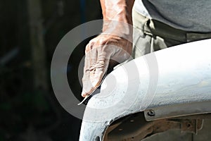 Automotive paint technician using grinder paper on car bumper,As part of the procedure to paint a new bumper car