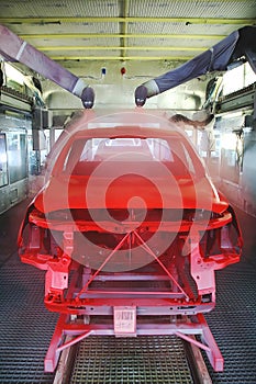 An auto body is spray painted by industrial robots in a paint shop. photo