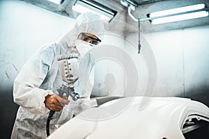 Automotive service worker in full protective gear painting bodywork. Oxus