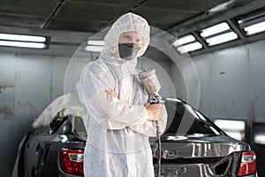 Automotive service worker in protective gear painting bodywork. Oxus