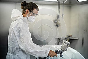 Automotive service worker in protective gear painting bodywork. Oxus