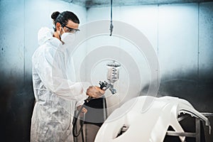 Automotive service worker in protective gear painting bodywork. Oxus
