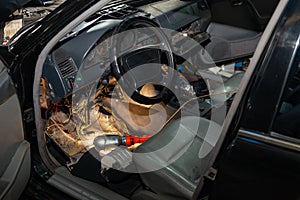 Automotive wiring under the wheel of an old German car, a disassembled dashboard for repairing and connecting electrical