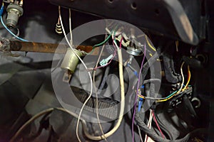 Automotive wiring under the wheel of an old russian retro car, a disassembled dashboard and seats for repairing and connecting