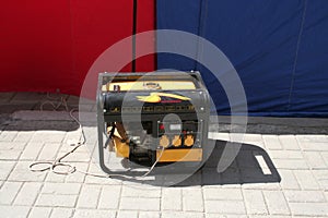 An autonomous portable diesel generator for supplying electricity in yellow stands on the street