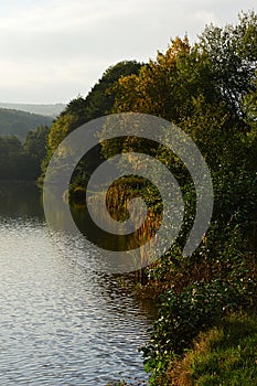 Jesenné popoludnie s pekne sfarbenými listnatými stromami na brehu jazera Jelenec - Remitaz, západné Slovensko.