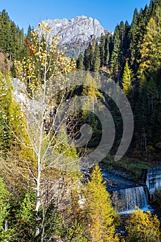 Autumn alpine Dolomites mountain view with small waterfall, Sudtirol, Italy