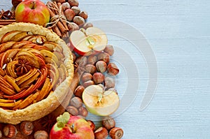 Autumn apple pie decorated with various ingredients - fresh sliced apples, hazelnuts, spices - anise, cinnamon. Thanksgiving tart