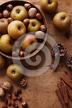 Autumn apples with nuts and cinnamon sticks on table