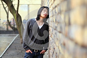 Autumn Asian man looking up lean on the wall