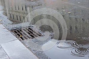 Autumn asphalt, metal grating stormwater on a city street. Autumn rainy weather with puddles, outflow of water from the highway. photo