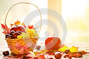 Autumn background with basket with yellow maple leaves, grapes, red apples. Frame of fall harvest on aged wood with copy space