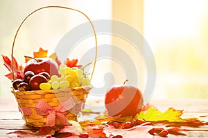 Autumn background with basket with yellow maple leaves, grapes, red apples. Frame of fall harvest on aged wood with copy space.